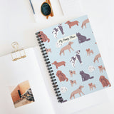 Notebook with dog illustrations placed on a white desk beside accessories