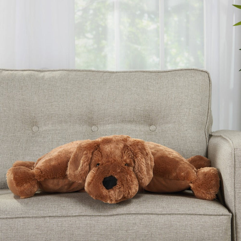 Stuffed brown dog pillow placed on light gray sofa in daylight
