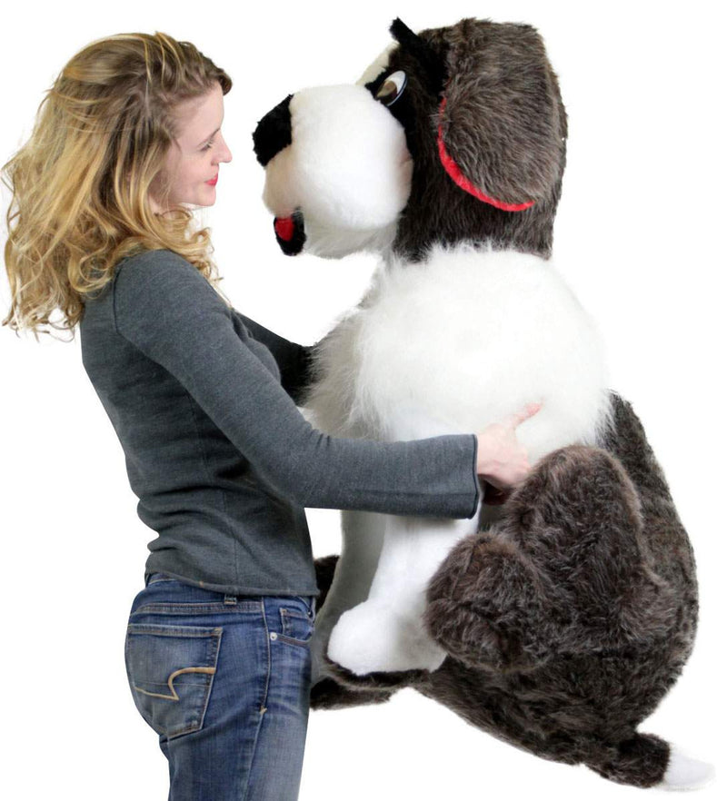 Side view of girl hugging giant plush Saint Bernard stuffed dog toy